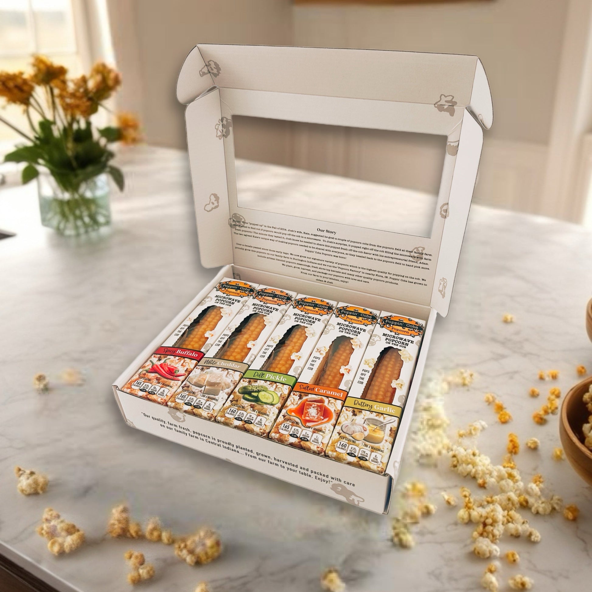 Open box of assorted snacks on a marble countertop with popcorn scattered around