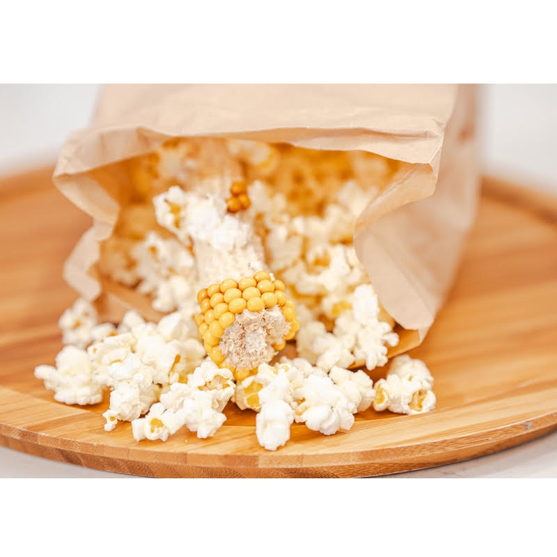Popped Popcorn and Cob spilling out of included brown paper bag onto wood surface