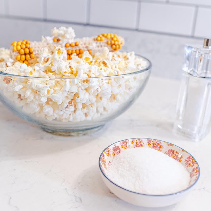 Glass Bowl with popped popcorn and leftover cob with salt in the foreground